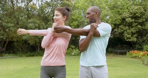Diverse couple relaxing outdoors stretching together in garden