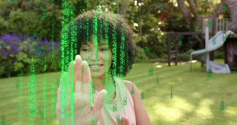 Young woman reaching through green code overlay in backyard using augmented reality