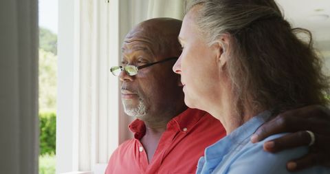 Senior Couple Embracing by Bright Window Indoors