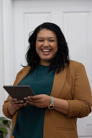 Smiling professional woman holding tablet in modern bright office for business branding