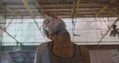 Female athlete tilting head upward in industrial gym with double-exposure financial graphs