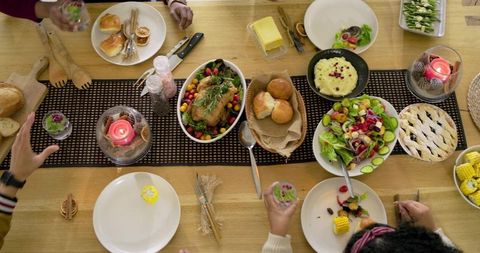 Friends Reaching for Roasted Chicken and Fresh Salad at Cozy Candlelit Dinner Table