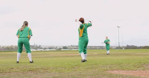 Female baseball team practicing on grassy field