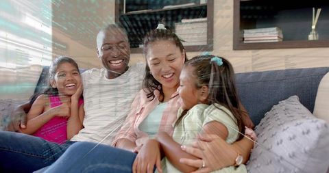 Happy family cuddling on sofa at home parents and daughters sharing joyful moment