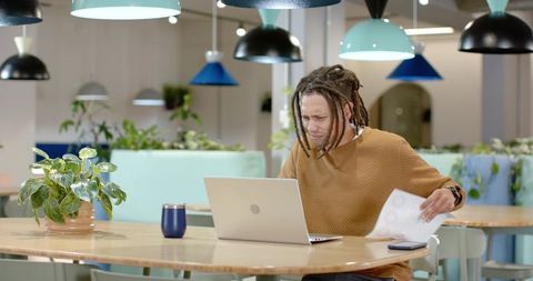 Frustrated African American Man Working on Laptop in Modern Coworking Space with Plants