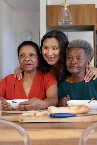 African american women sharing meal and warm embrace in home kitchen, generations together