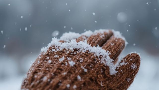 Brown knitted mitten catching fresh snowflakes closeup macro winter texture