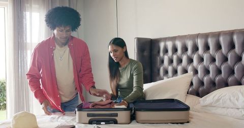Diverse Couple Packing Suitcase in Modern Bedroom