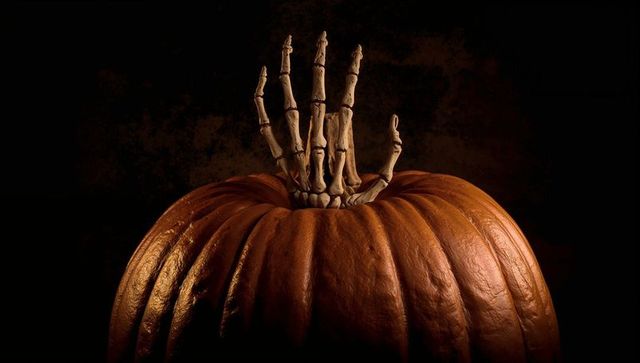 Skeletal Hand Emerging from Orange Pumpkin for Halloween Theme