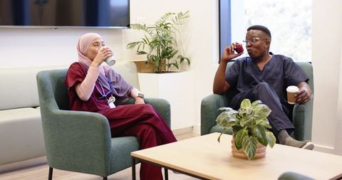 Healthcare staff relaxing in lounge sipping coffee during break with stethoscope