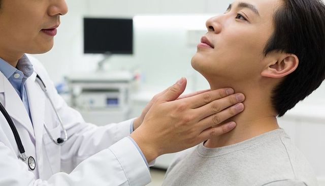 Doctor palpating patient neck during thyroid examination in modern clinic consultation