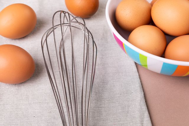 Close-up of raw brown eggs with wire whisk on table. unaltered, food, preparation and healthy eating concept.