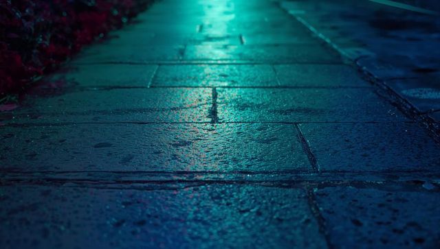 Wet pavement reflecting neon blue light at night