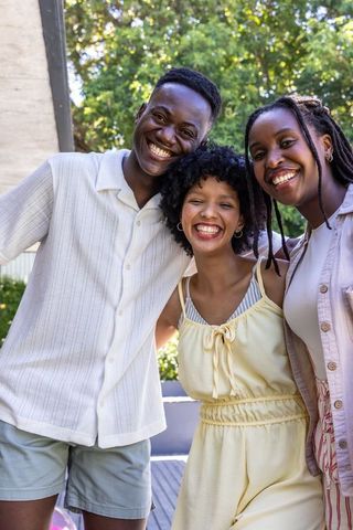 Smiling african friends posing on sunlit backyard deck, summer lifestyle portrait