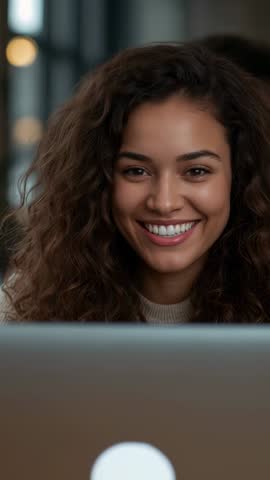 Vertical video: Young woman smiling while working on laptop in cozy cafe