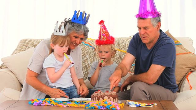 This lively scene shows grandparents and children enjoying a heartfelt birthday celebration. Ideal for family-oriented use, showcasing togetherness, multigenerational bonding, and joyous occasions. Perfect for advertisements or articles about family life, gatherings, and celebratory moments.