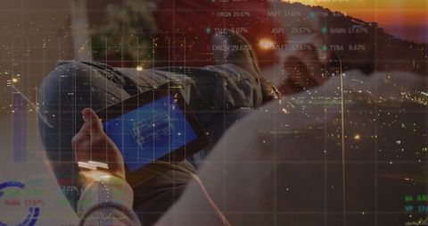 Reclining Asian man viewing tablet blueprint with city data overlay at dusk