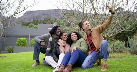Friends Taking Selfie on Green Lawn Outside Modern Building Laughing Together