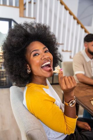 Cheerful Woman Enjoying Dessert at Home Dining Table