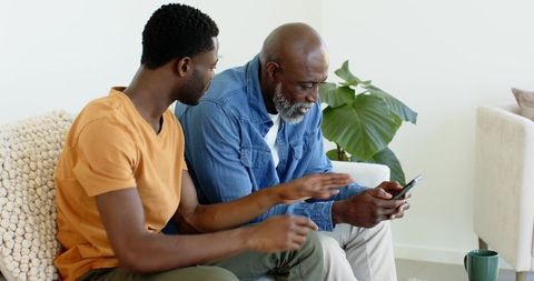 Father and Son Connecting over Smartphone in Cozy Living Room