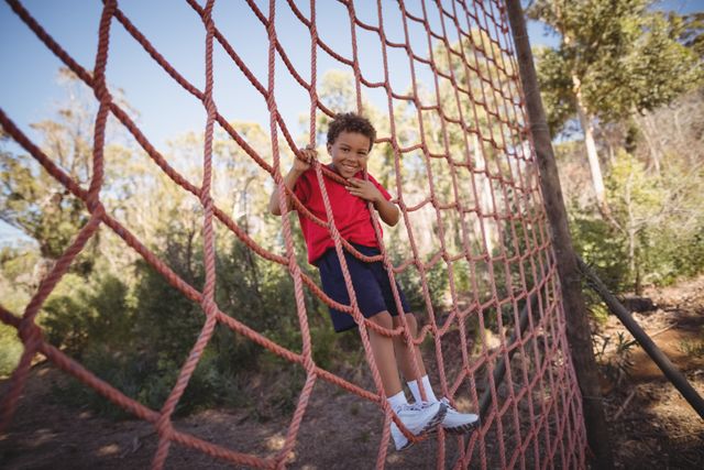 Portrait of happy boy climbing a net during obstacle course - Download Free Stock Photos Pikwizard.com