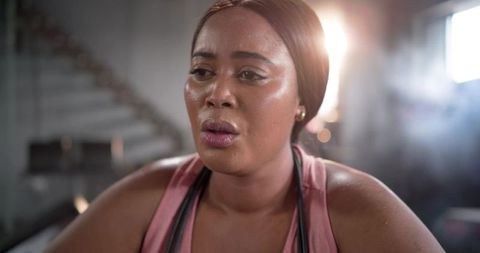 African american woman wiping sweat and catching breath after intense gym workout