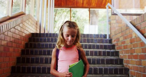 Young Schoolgirl Holding Books on Staircase with Sunlight