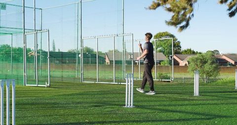 Cricketer walking through practice nets during sunny suburban training session