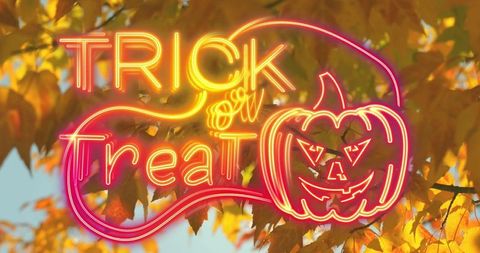 Neon trick or treat sign over autumn leaves for halloween