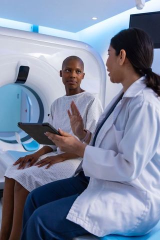 Female clinician consulting african american patient at mri gantry discussing scan results