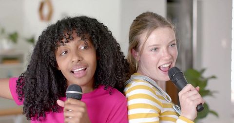 Diverse teenagers joyfully singing karaoke at home