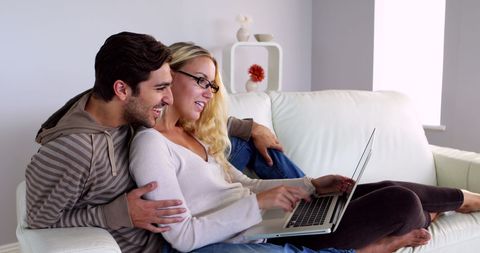 Happy Couple Relaxing on Couch Using Laptop Together