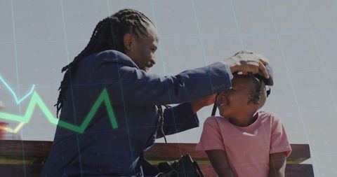 Father placing headphones on smiling son on park bench sunny day family bonding outdoor