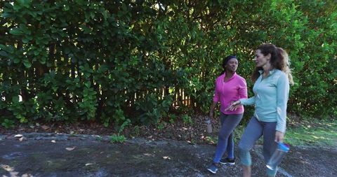 Diverse Women Enjoying Fitness Walk with Water Bottles in Green Park