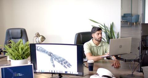 Professional man utilizes laptop with robotic arm display in modern office