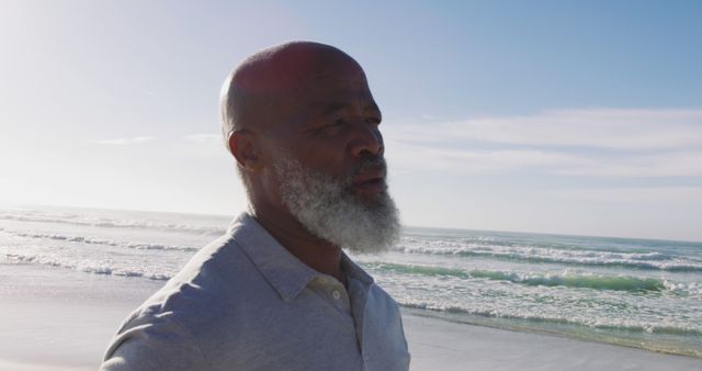 Senior african american man standing at the beach, admiring the view, closing eyes. healthy outdoor leisure time by the sea.
