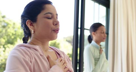 Sunlit mindful breathing session with women practicing heart meditation, wellness at home