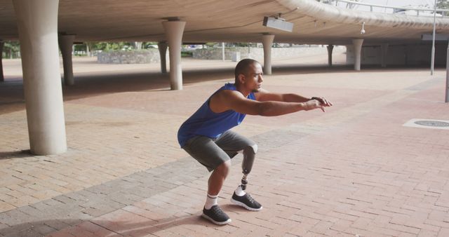 Biracial man doing squats with his prosthetic leg in city. Sport, active lifestyle and disability.