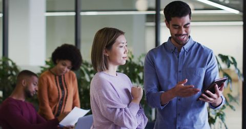 Diverse Professionals Collaborating with Digital Tablet in Modern Office