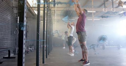 Three Men Engaged in Overhead Throws at CrossFit Gym