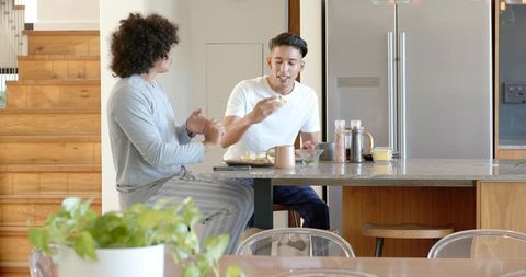 Two friends enjoying breakfast chat in modern kitchen