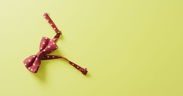 Image of red dotted bow tie lying on yellow background. men fashion, clothes, accessories and elegance concept.