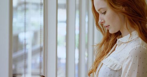 Young Woman Dreamily Gazing Out Home Window