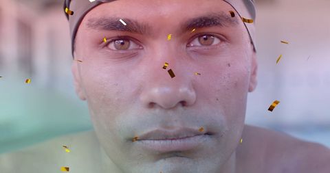 Focused Biracial Male Swimmer with Falling Confetti in Pool