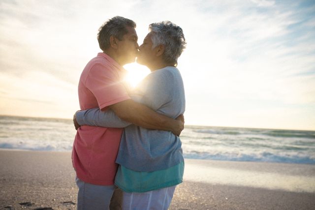 Side view of affectionate senior couple embracing while kissing each other at beach during sunset. lifestyle, love and weekend.