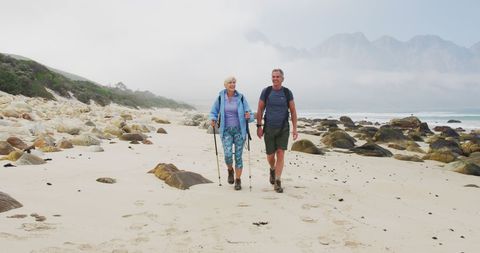 Senior Couple Hiking with Poles on Coastal Beach