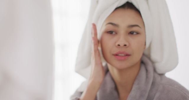 Image of portrait of smiling biracial woman with towel on hair looking in mirror in bathroom - Download Free Stock Photos Pikwizard.com