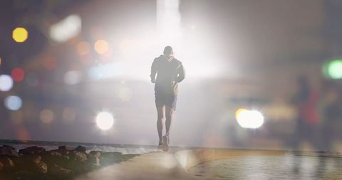 Man Running by the Sea Framed by City Lights at Night - Download Free Stock Images Pikwizard.com