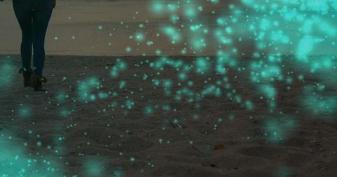 Walking along dusky shore in denim and boots with teal light particles and moody coastal glow
