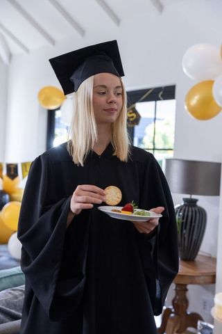 Graduation celebration party: female graduate enjoying snacks at home